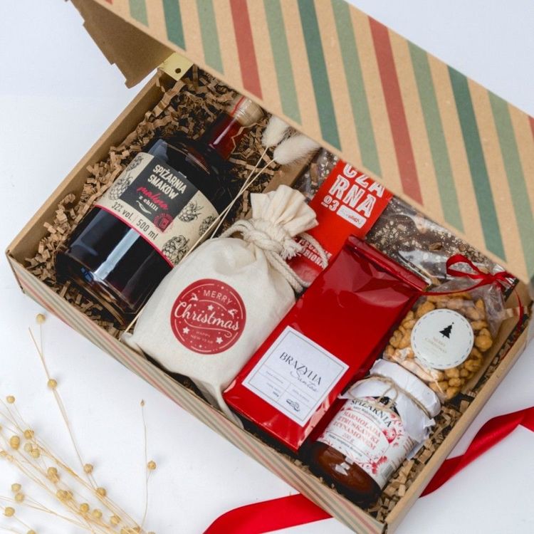 Świąteczne pudełko kraft w paski z otwartym wieczkiem, butelka malin z chilli, słoik truskawek z cynamonem i słodycze