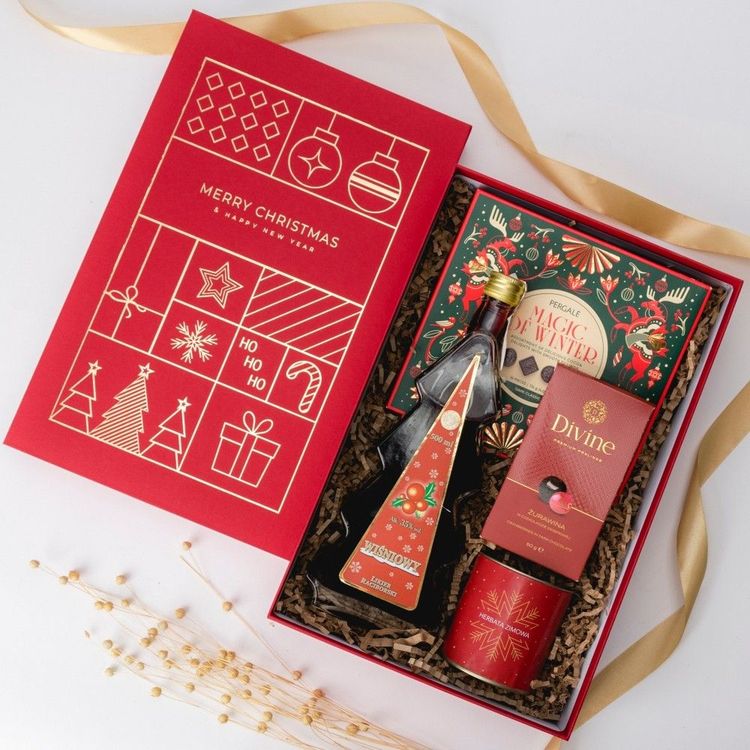 Świąteczne czerwone pudełko prostokątne z butelką likieru wiśniowego, pudełkami słodyczy i puszką herbaty zimowej