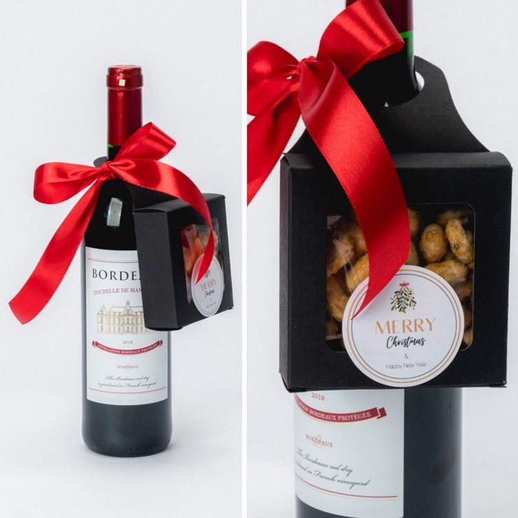 Świąteczny zestaw w czarnym pudełku prostokątnym z okienkiem i uchwytem, butelką czerwonego wina i orzeszkami w karmelu