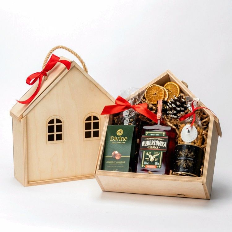 Drewniana skrzynka w kształcie domu z uchwytami sznurkowymi, butelką, puszką kawy i orzechami w czekoladzie