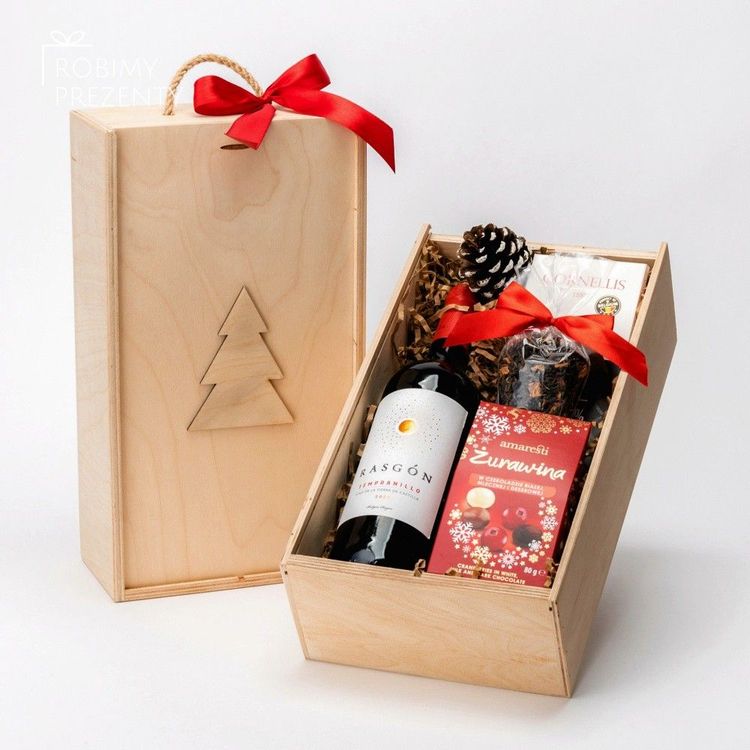 Świąteczna drewniana skrzynia z czerwonym winem, żurawiną w czekoladzie, herbatą, wstążką i szyszką