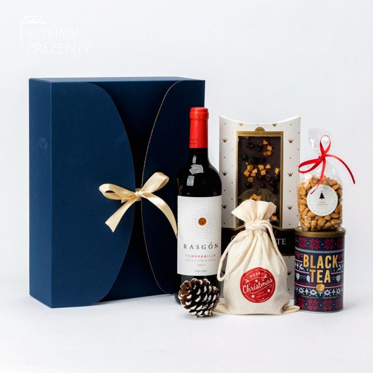 Świąteczny zestaw w granatowym pudełku z kokardą, czerwonym winem, czekoladą i herbatą