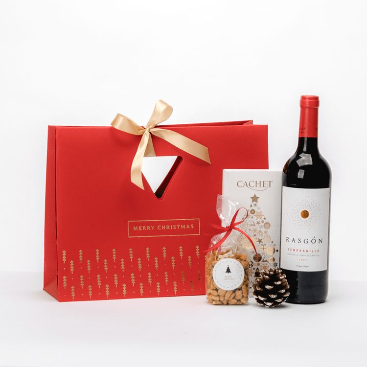 Czerwona papierowa torba świąteczna ze wstążką i okienkiem z winem Rasgón, czekoladą Cachet i orzeszkami