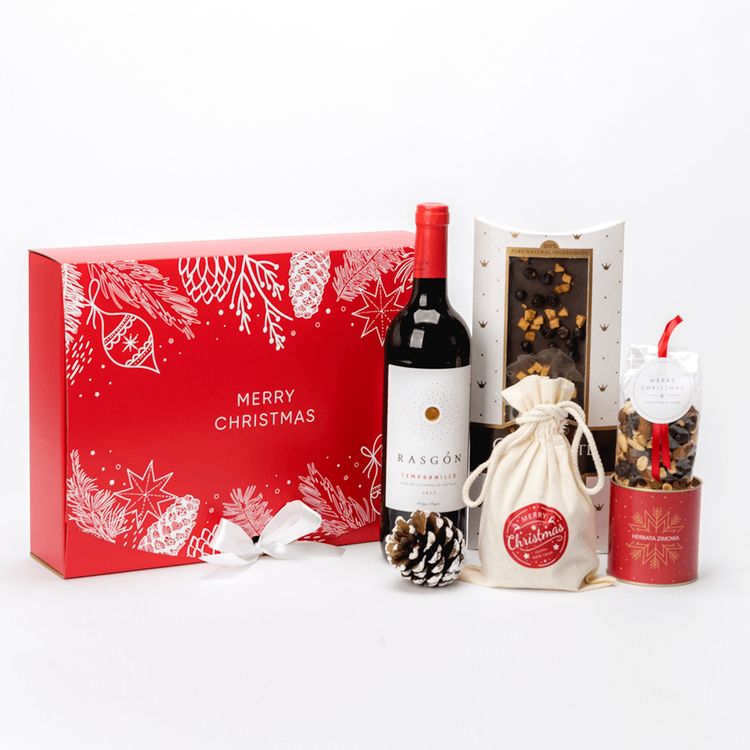 Czerwone pudełko świąteczne z butelką czerwonego wina, herbatą zimową, piernikami i bakaliami ze wstążką