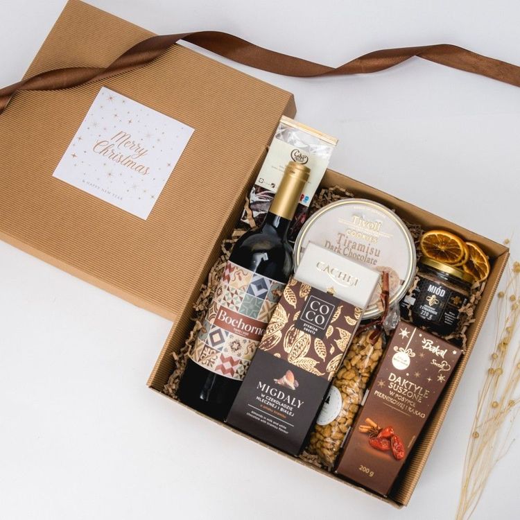 Świąteczny zestaw w pudełku kraft z czerwonym winem, miodem, ciastkami tiramisu i czekoladą