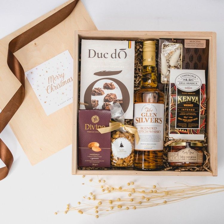 Świąteczna drewniana skrzynia z butelką whisky, czekoladami, kawą i przysmakami