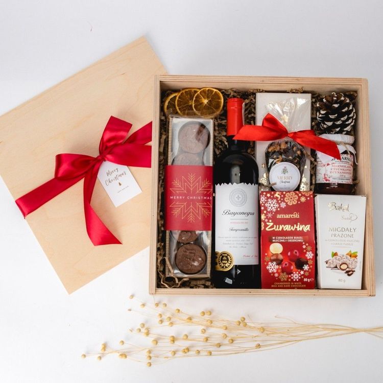 Świąteczna drewniana skrzynka z czerwonym winem, czekoladami, herbatą i marmoladą