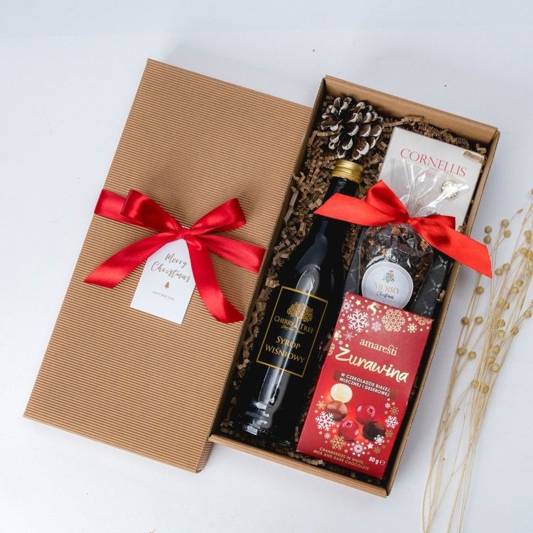 Świąteczne pudełko kraft z czerwoną wstążką, syropem wiśniowym i żurawiną w czekoladzie