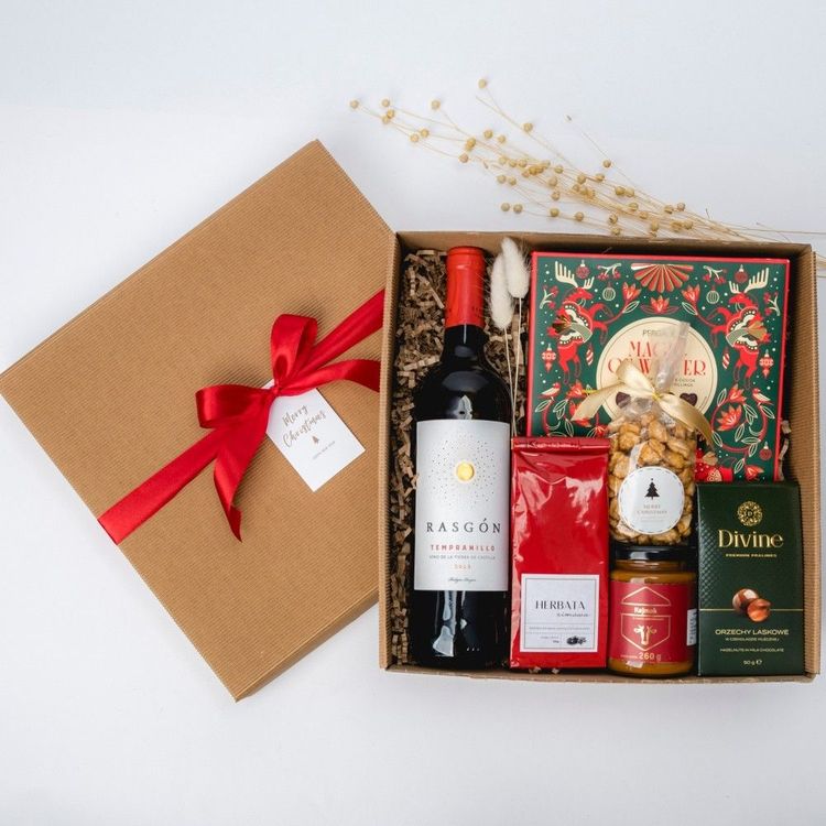 Świąteczne brązowe pudełko kraft z czerwoną wstążką, winem Tempranillo i słodyczami